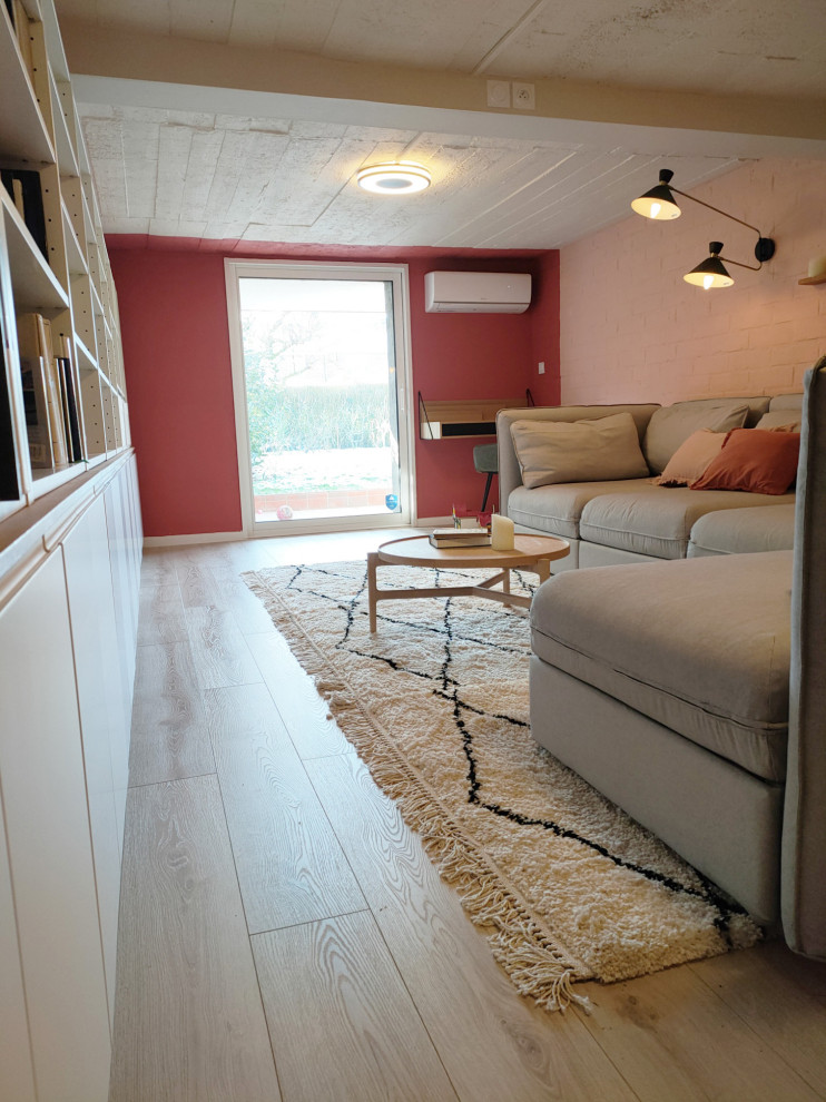 Cette image montre un sous-sol minimaliste donnant sur l'extérieur et de taille moyenne avec un mur rose, sol en stratifié et aucune cheminée.