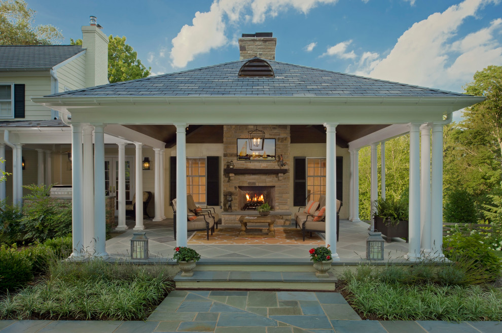 Immagine di un patio o portico classico dietro casa con un caminetto, pavimentazioni in pietra naturale e un gazebo o capanno