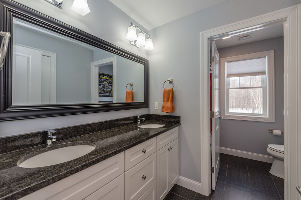 Design ideas for a mid-sized transitional 3/4 bathroom in New York with shaker cabinets, white cabinets, an alcove tub, a shower/bathtub combo, a two-piece toilet, grey walls, an undermount sink, granite benchtops, a shower curtain, vinyl floors and black floor.