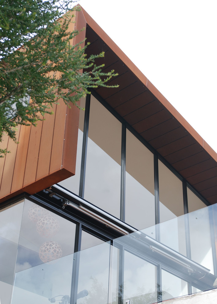 Large contemporary two-storey brown house exterior in Adelaide with metal siding, a shed roof and a metal roof.