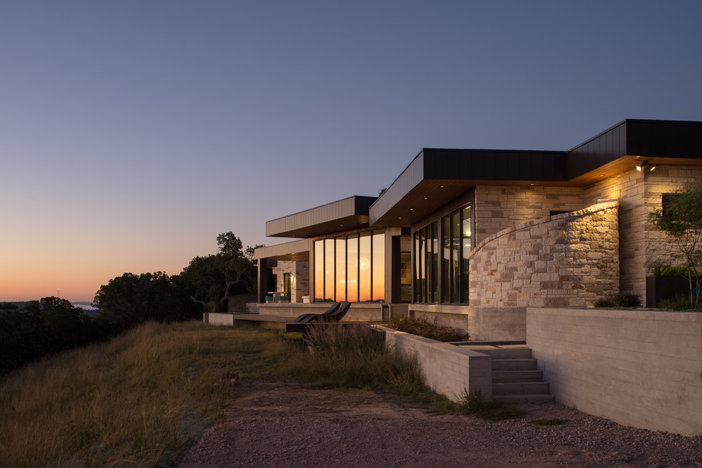 Photo of a large contemporary one-storey black house exterior in Austin with metal siding, a flat roof and a metal roof.