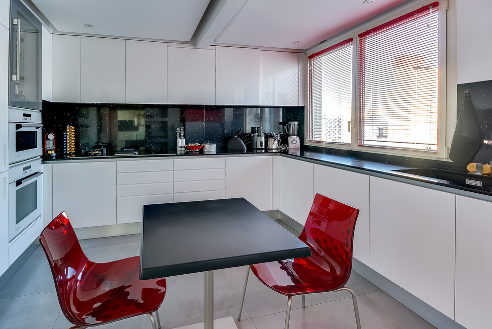 Photo of a mid-sized contemporary u-shaped eat-in kitchen in Paris with flat-panel cabinets, black splashback, white appliances and no island.