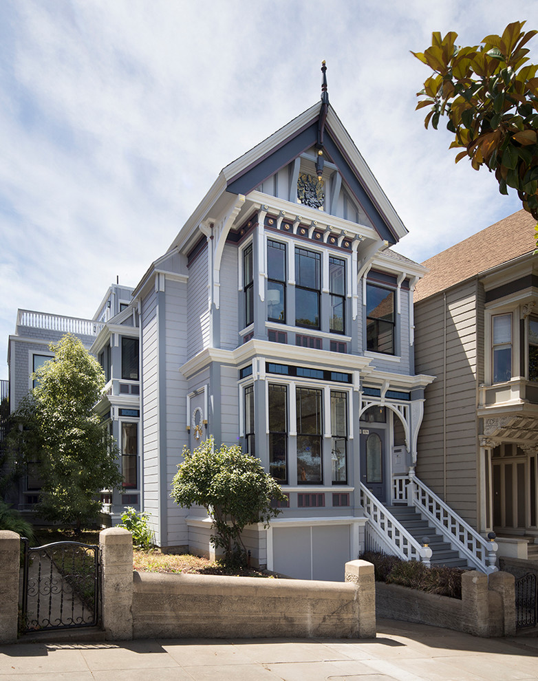 This is an example of a large traditional two-storey blue house exterior in San Francisco with vinyl siding, a gable roof and a shingle roof.