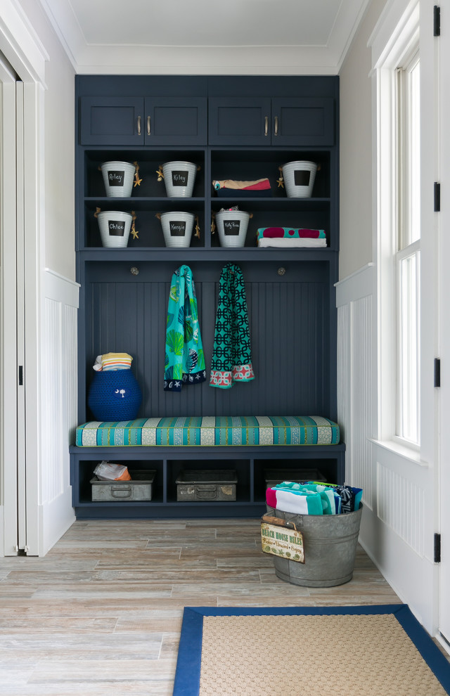 This is an example of a beach style mudroom in Charleston with beige walls and brown floor.