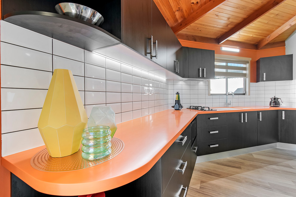 Photo of a small modern single-wall separate kitchen in Sunshine Coast with an integrated sink, solid surface benchtops, yellow splashback, subway tile splashback and orange benchtop.
