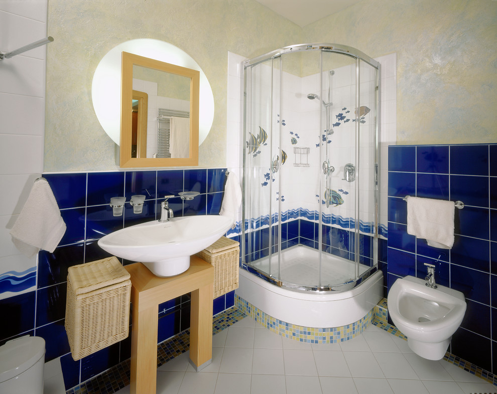 На фото: ванная комната среднего размера с фасадами цвета дерева среднего тона, гидромассажной ванной, угловым душем, инсталляцией, синей плиткой, керамической плиткой, желтыми стенами, полом из керамогранита, душевой кабиной, раковиной с пьедесталом, белым полом и душем с раздвижными дверями с