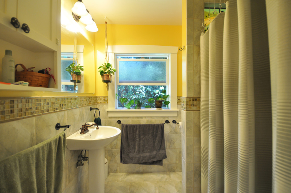 This is an example of a small arts and crafts 3/4 bathroom in Seattle with a pedestal sink, shaker cabinets, white cabinets, an alcove shower, a one-piece toilet, gray tile, porcelain tile, yellow walls and porcelain floors.