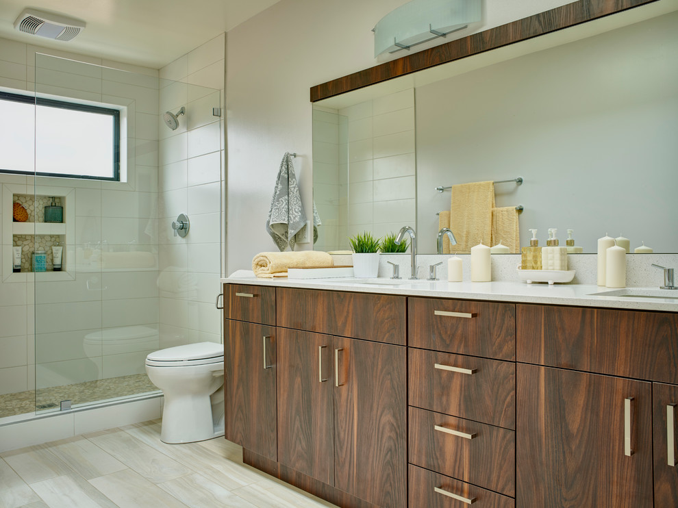 Photo of a large contemporary master bathroom in Los Angeles with flat-panel cabinets, medium wood cabinets, an alcove shower, a two-piece toilet, white tile, ceramic tile, white walls, plywood floors, an undermount sink and solid surface benchtops.