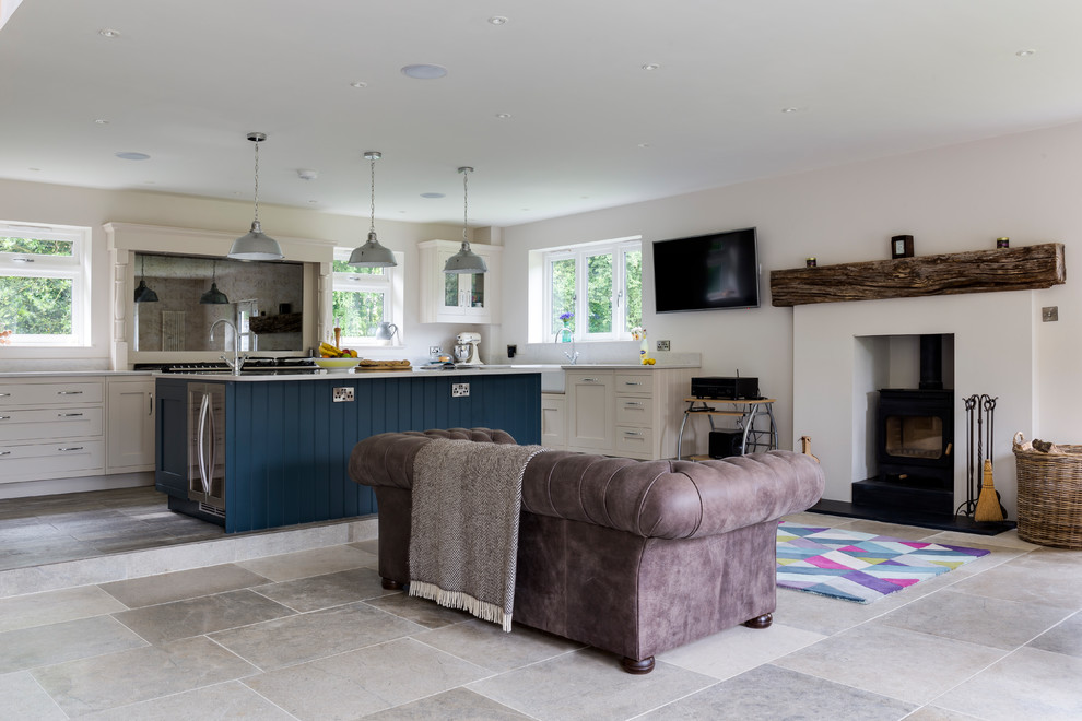 Large transitional open concept family room in Wiltshire with white walls, ceramic floors, a wood stove, a stone fireplace surround, a wall-mounted tv and grey floor.