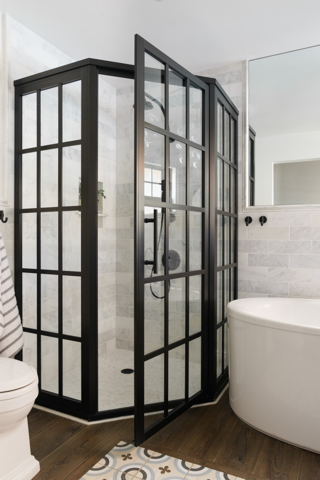 На фото: детская ванная комната среднего размера в стиле кантри с отдельно стоящей ванной, угловым душем, белой плиткой, мраморной плиткой, белыми стенами, полом из винила, коричневым полом и душем с распашными дверями