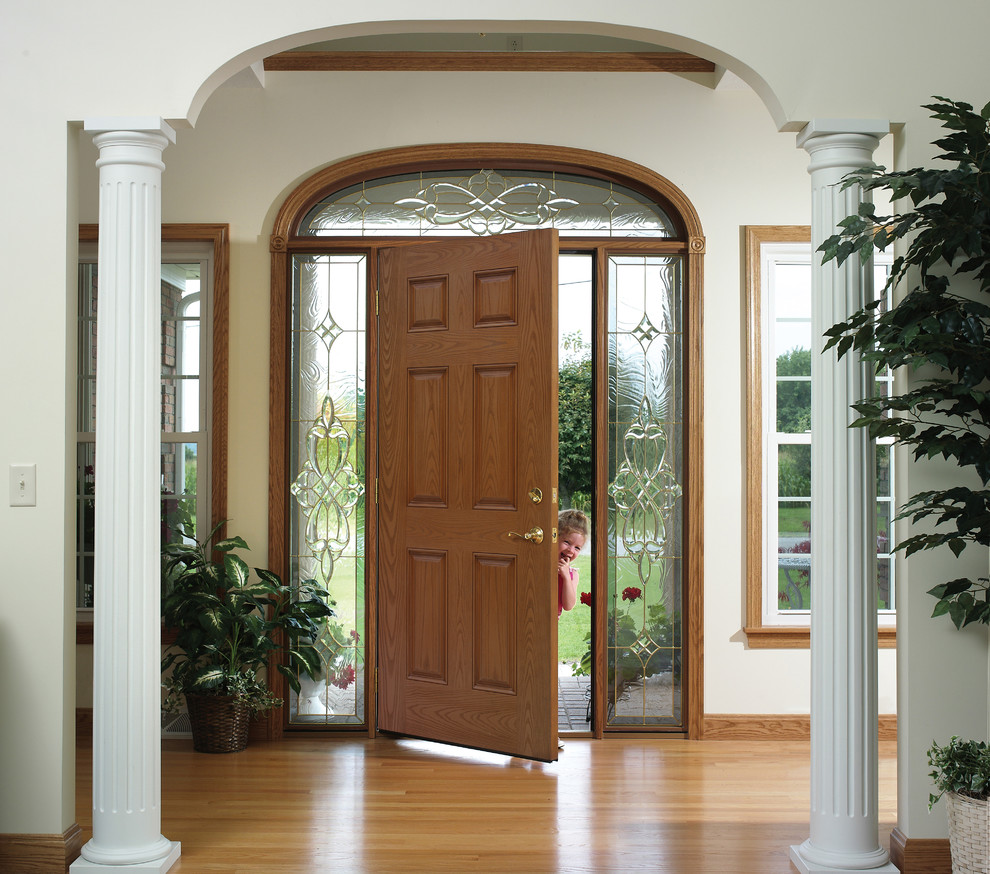 Photo of a large traditional front door in Other with brown walls, light hardwood floors, a single front door, a dark wood front door and grey floor.