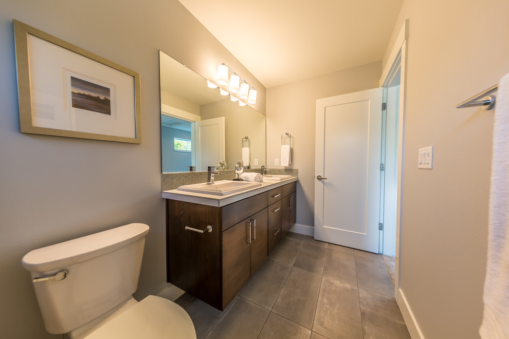 This is an example of a large contemporary kids bathroom in Portland with flat-panel cabinets, black cabinets, an alcove shower, gray tile, ceramic tile, grey walls, ceramic floors, a drop-in sink, tile benchtops, grey floor and a hinged shower door.
