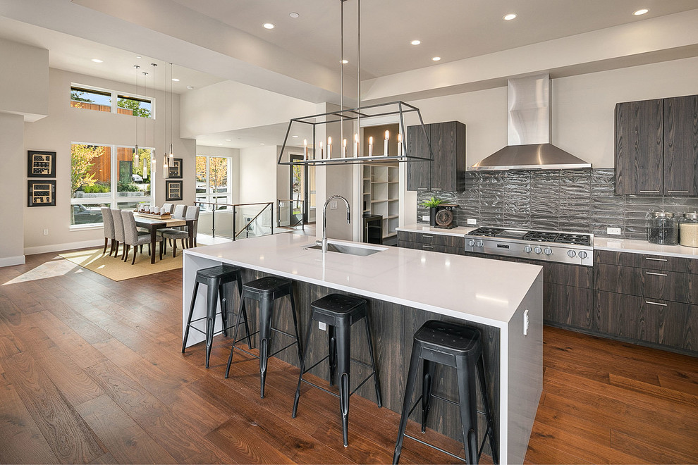Photo of a contemporary kitchen in Seattle with an undermount sink, flat-panel cabinets, dark wood cabinets, grey splashback, stainless steel appliances, dark hardwood floors, with island, brown floor and white benchtop.