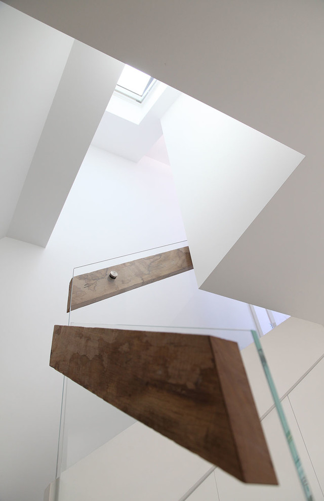 This is an example of a contemporary wood straight staircase in Sydney with carpet risers and glass railing.