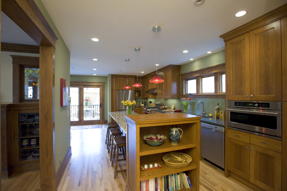Arts and crafts l-shaped kitchen in Minneapolis with mosaic tile splashback, stainless steel appliances, green splashback, medium wood cabinets, recessed-panel cabinets, an undermount sink and concrete benchtops.
