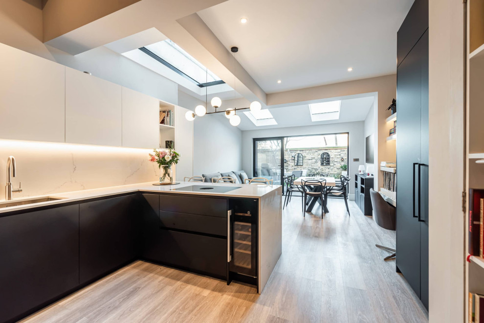 Design ideas for a small contemporary l-shaped open plan kitchen in London with an undermount sink, shaker cabinets, black cabinets, quartzite benchtops, beige splashback, engineered quartz splashback, black appliances, light hardwood floors, grey floor, white benchtop and coffered.