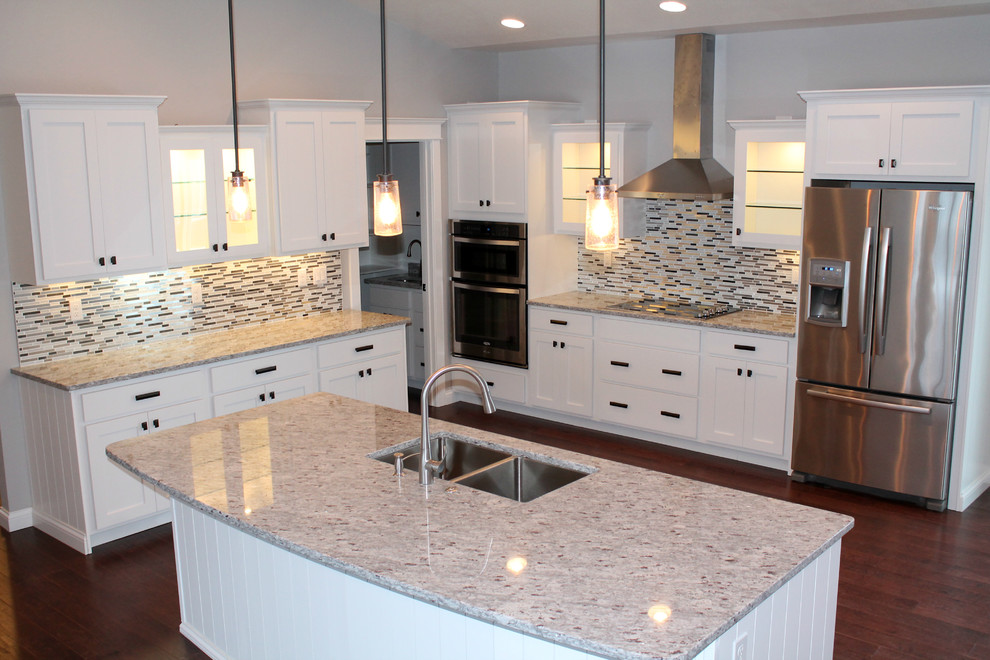 Eat-in kitchen - large transitional l-shaped medium tone wood floor eat-in kitchen idea with a double-bowl sink, recessed-panel cabinets, white cabinets, granite countertops, glass tile backsplash, stainless steel appliances, an island and multicolored backsplash