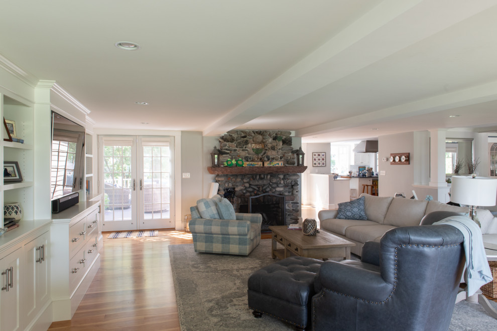 This is an example of a transitional living room in Boston with white walls, light hardwood floors, a standard fireplace, a stone fireplace surround, a built-in media wall and brown floor.