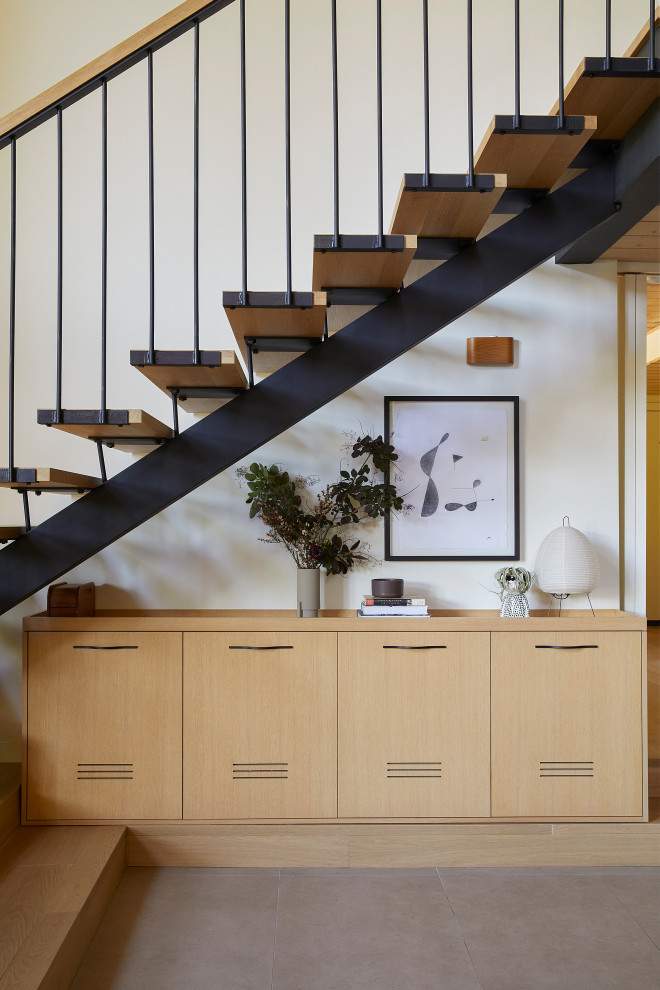Cette image montre un escalier flottant vintage de taille moyenne avec des marches en bois et un garde-corps en métal.