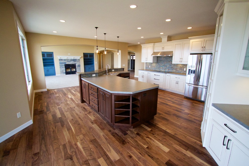 Open concept kitchen - huge open concept kitchen idea with raised-panel cabinets, dark wood cabinets, solid surface countertops and an island