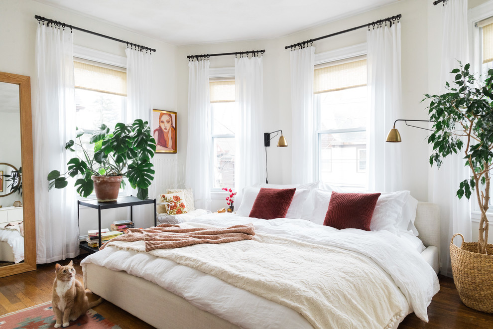 This is an example of an eclectic master bedroom in Boston with white walls, dark hardwood floors and no fireplace.