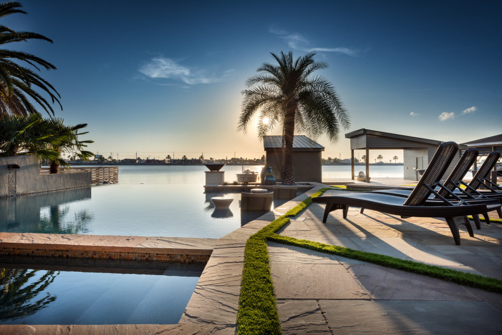 Esempio di una grande piscina a sfioro infinito minimalista personalizzata dietro casa con pavimentazioni in pietra naturale