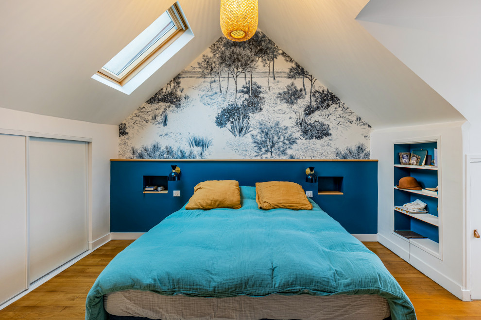 This is an example of a large contemporary bedroom in Paris with blue walls, light hardwood flooring, brown floors, exposed beams and wallpapered walls.
