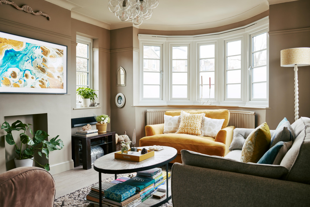 This is an example of a classic living room in London with brown walls, a wall mounted tv, light hardwood flooring and beige floors.