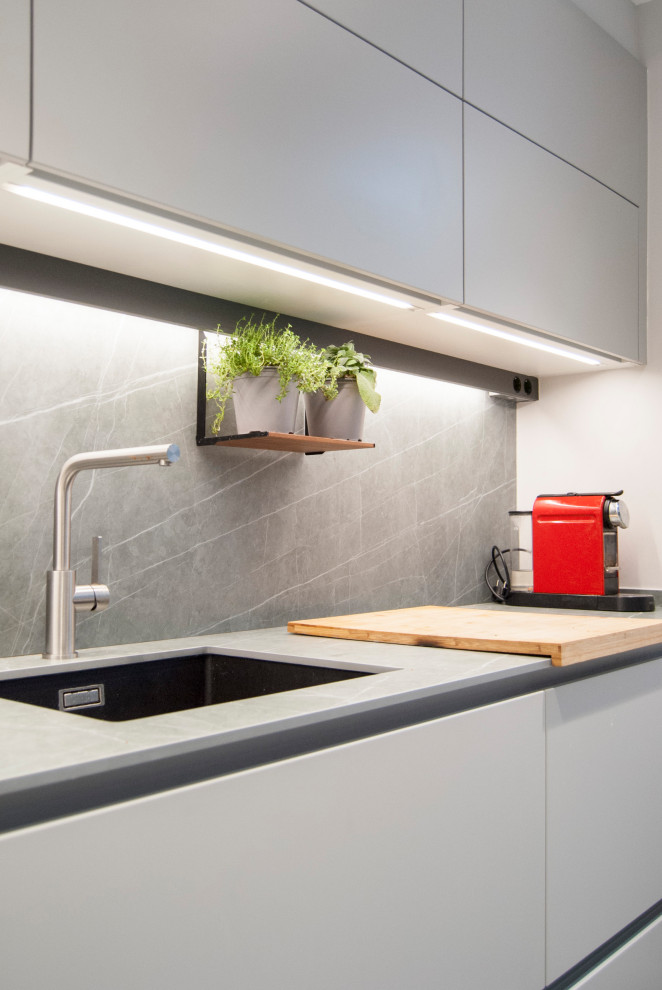 Idéer för ett avskilt, mellanstort modernt grå l-kök, med en undermonterad diskho, släta luckor, grå skåp, grått stänkskydd, rostfria vitvaror, en halv köksö och grått golv