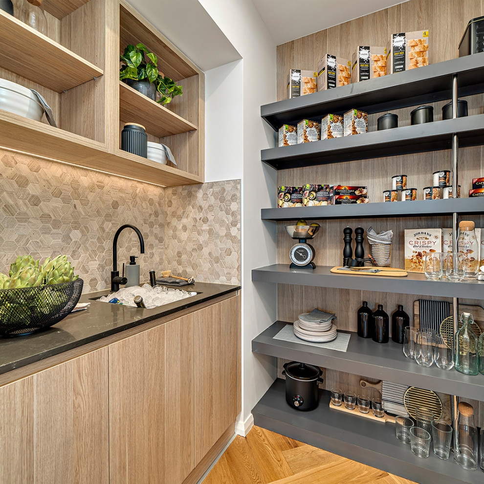 This is an example of a mid-sized contemporary galley kitchen pantry in Sydney with a single-bowl sink, open cabinets, brown cabinets, quartz benchtops, beige splashback, mosaic tile splashback, black appliances, medium hardwood floors, with island and black benchtop.