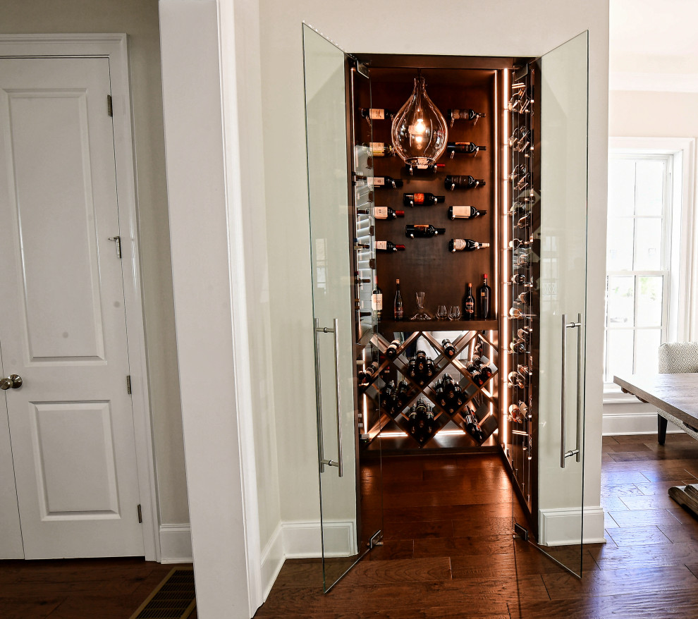 Small transitional wine cellar in Atlanta with dark hardwood floors, diamond bins and brown floor.