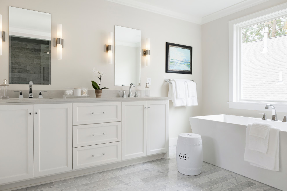 Photo of a large transitional master bathroom in Minneapolis with shaker cabinets, white cabinets, a freestanding tub, an alcove shower, beige tile, beige walls, marble floors, an undermount sink, white floor, grey benchtops, a double vanity, a built-in vanity and engineered quartz benchtops.