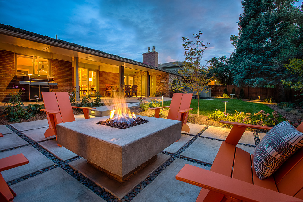This is an example of a mid-sized midcentury backyard patio in Denver with a fire feature and concrete pavers.