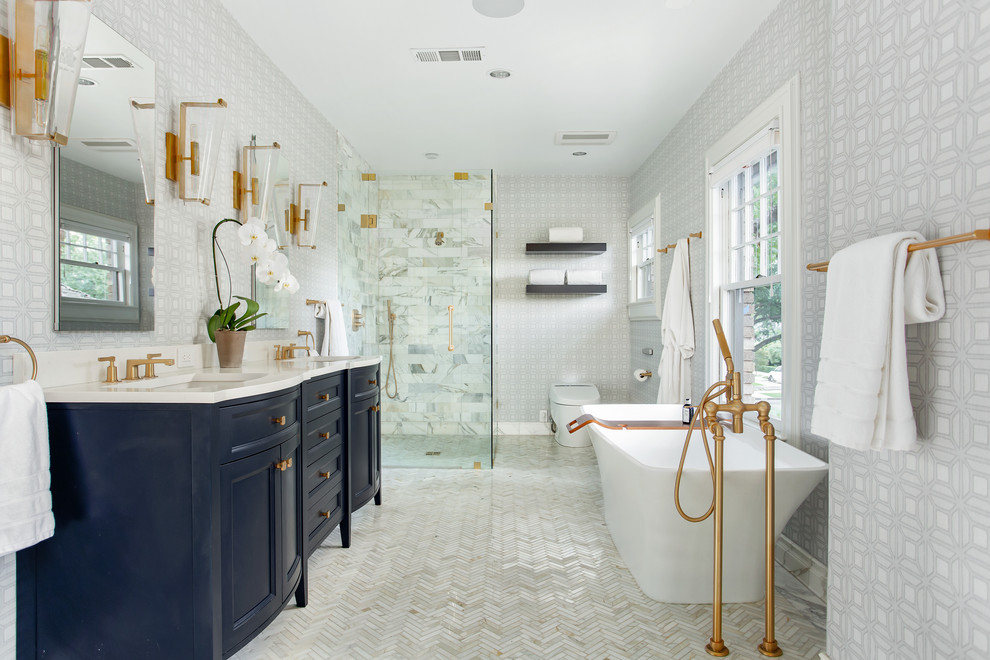 Design ideas for a large contemporary master bathroom in Dallas with furniture-like cabinets, blue cabinets, a freestanding tub, a curbless shower, a one-piece toilet, white tile, marble, blue walls, marble floors, an undermount sink, engineered quartz benchtops, white floor, a hinged shower door and white benchtops.