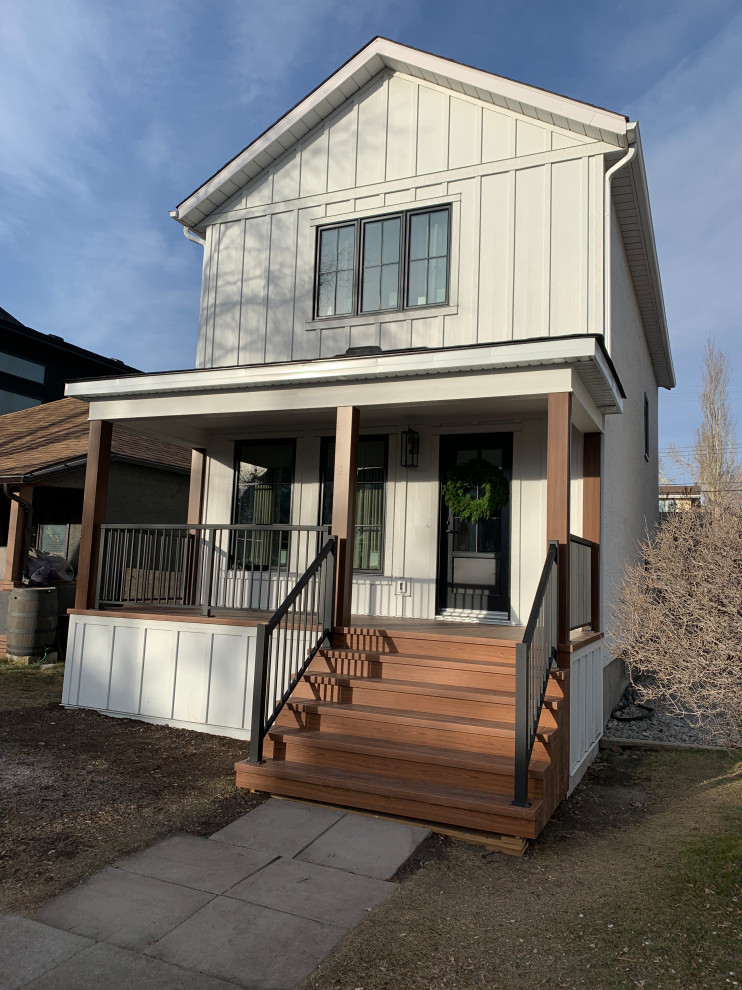 Inspiration for a mid-sized traditional two-storey white house exterior in Calgary with concrete fiberboard siding, a black roof and board and batten siding.