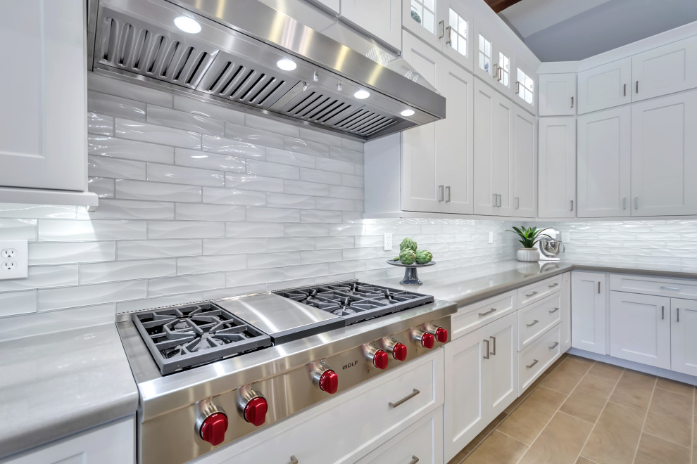Example of a large transitional l-shaped porcelain tile and brown floor eat-in kitchen design in Phoenix with a farmhouse sink, shaker cabinets, white cabinets, quartz countertops, white backsplash, subway tile backsplash, stainless steel appliances, an island and gray countertops