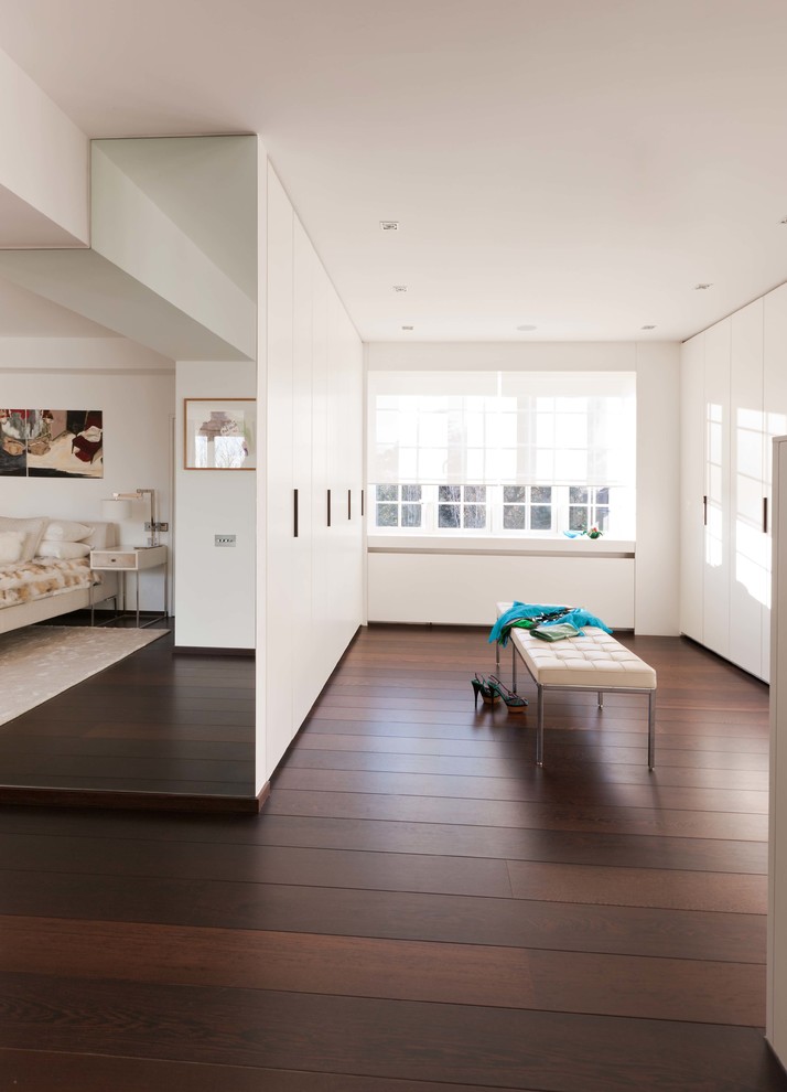 Design ideas for a large contemporary gender-neutral walk-in wardrobe in London with flat-panel cabinets, white cabinets, dark hardwood floors and brown floor.