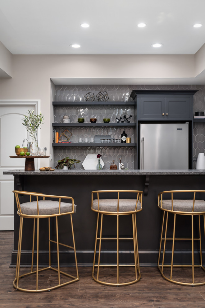 Design ideas for a large transitional galley seated home bar in Chicago with vinyl floors, brown floor, shaker cabinets, grey cabinets, grey splashback and grey benchtop.