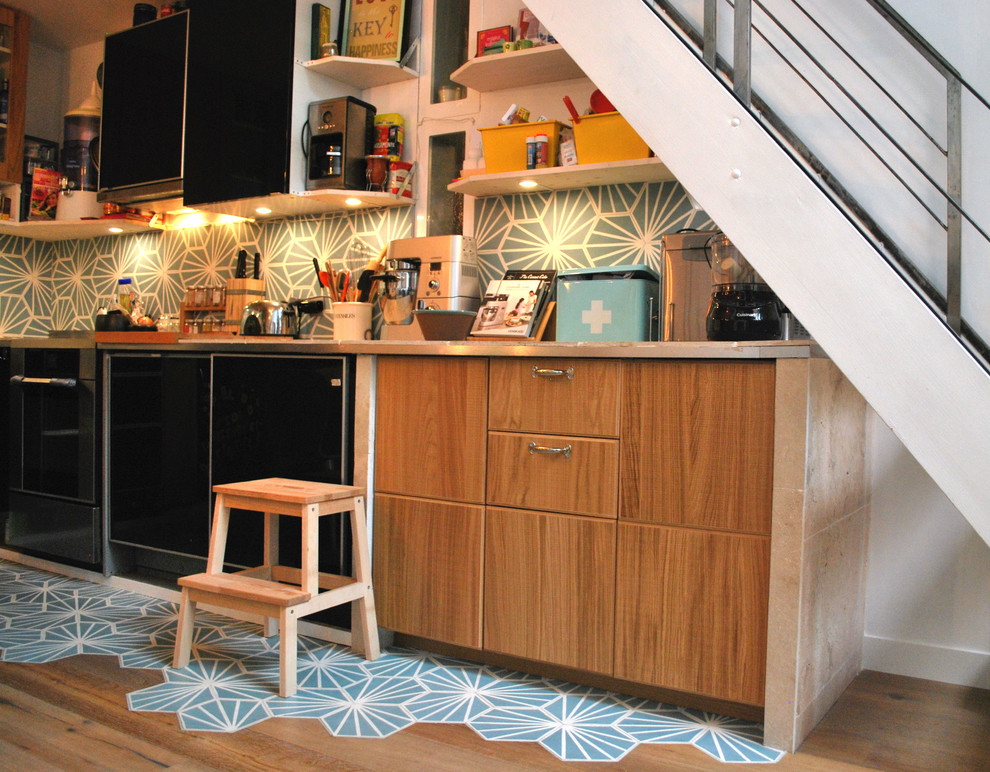 This is an example of a mid-sized scandinavian l-shaped open plan kitchen in Paris with light wood cabinets, tile benchtops, cement tile splashback and no island.