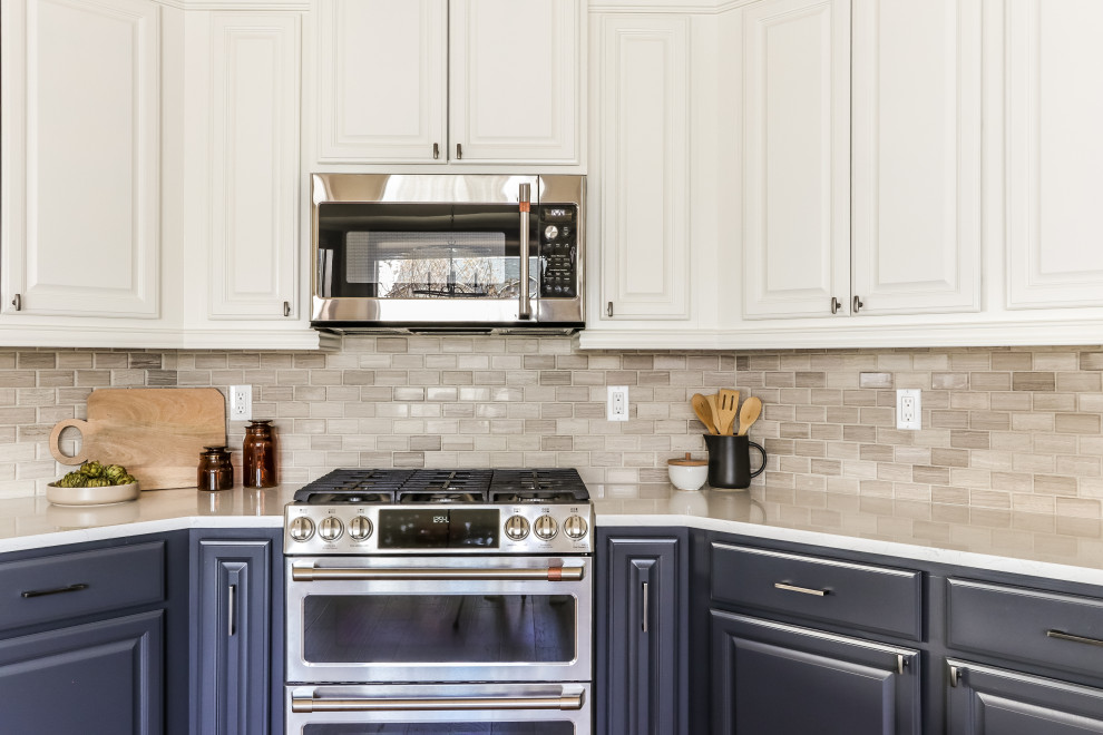 Inspiration for a mid-sized transitional u-shaped medium tone wood floor and brown floor kitchen remodel in Seattle with a farmhouse sink, white cabinets, quartz countertops, gray backsplash, marble backsplash, stainless steel appliances and white countertops