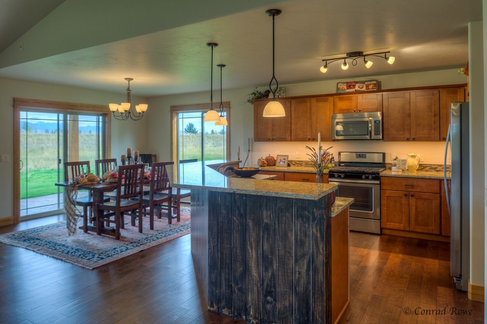 Example of a mid-sized mountain style u-shaped medium tone wood floor eat-in kitchen design with recessed-panel cabinets, medium tone wood cabinets, granite countertops, multicolored backsplash, mosaic tile backsplash, stainless steel appliances, an island and a double-bowl sink