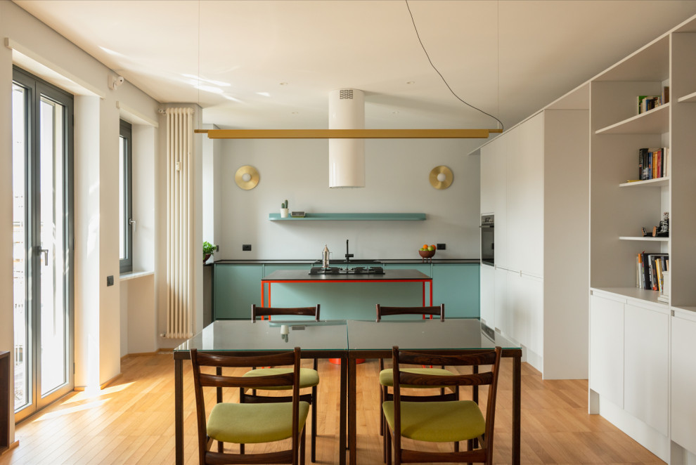 Inspiration for a large modern l-shaped kitchen/diner in Turin with a double-bowl sink, flat-panel cabinets, turquoise cabinets, black appliances, medium hardwood flooring, an island, black worktops and a drop ceiling.
