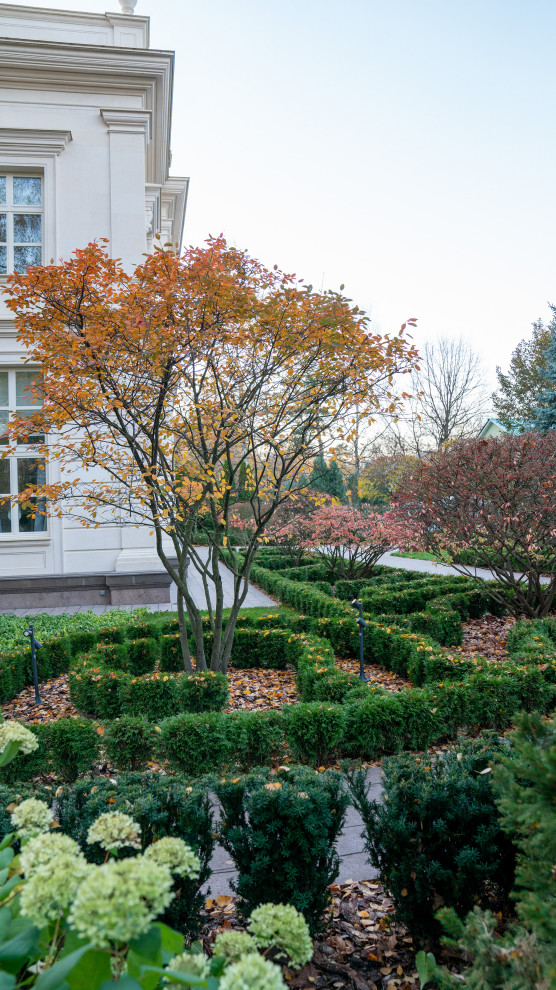 Imagen de jardín clásico renovado de tamaño medio en otoño en patio lateral con jardín francés, parterre de flores, exposición parcial al sol, adoquines de piedra natural y con madera