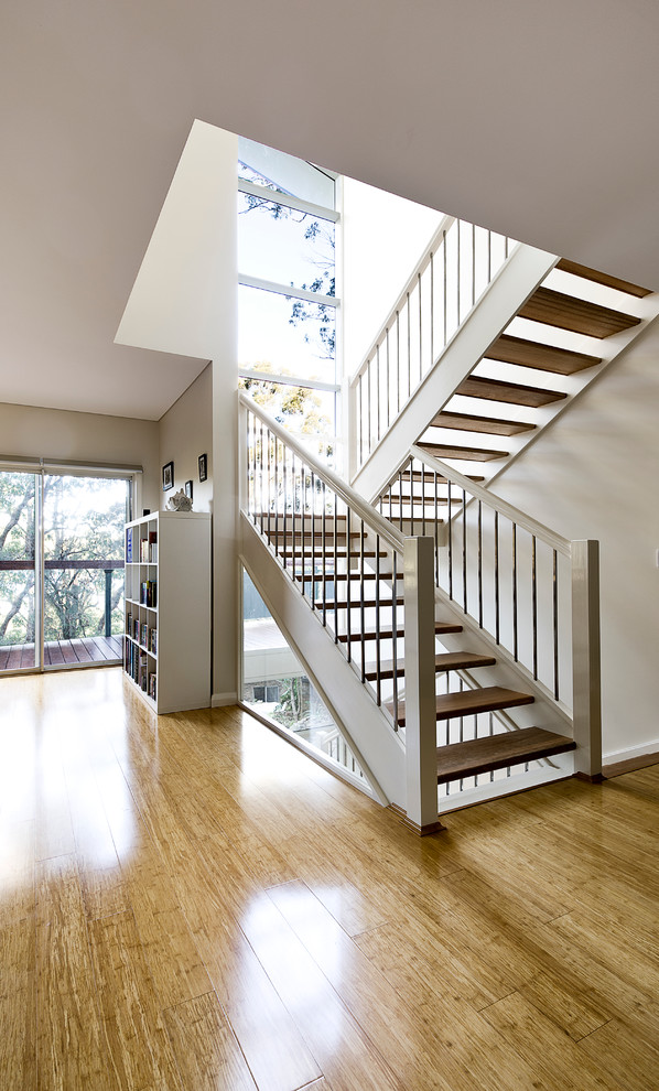 Photo of a large contemporary wood u-shaped staircase in Sydney with open risers and wood railing.