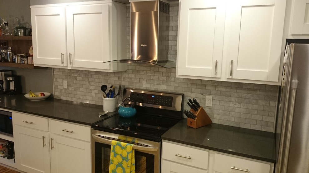 Example of a mid-sized transitional galley enclosed kitchen design in Orange County with an undermount sink, shaker cabinets, white cabinets, granite countertops, gray backsplash, subway tile backsplash, stainless steel appliances and an island