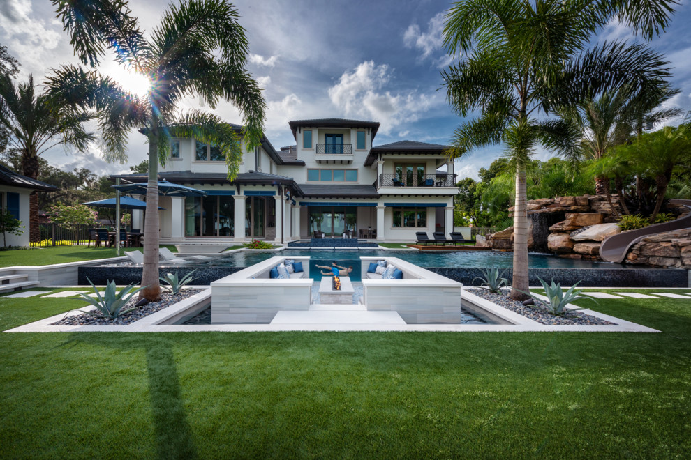 Large contemporary custom shaped infinity swimming pool in Tampa with with pool landscaping and tiled flooring.