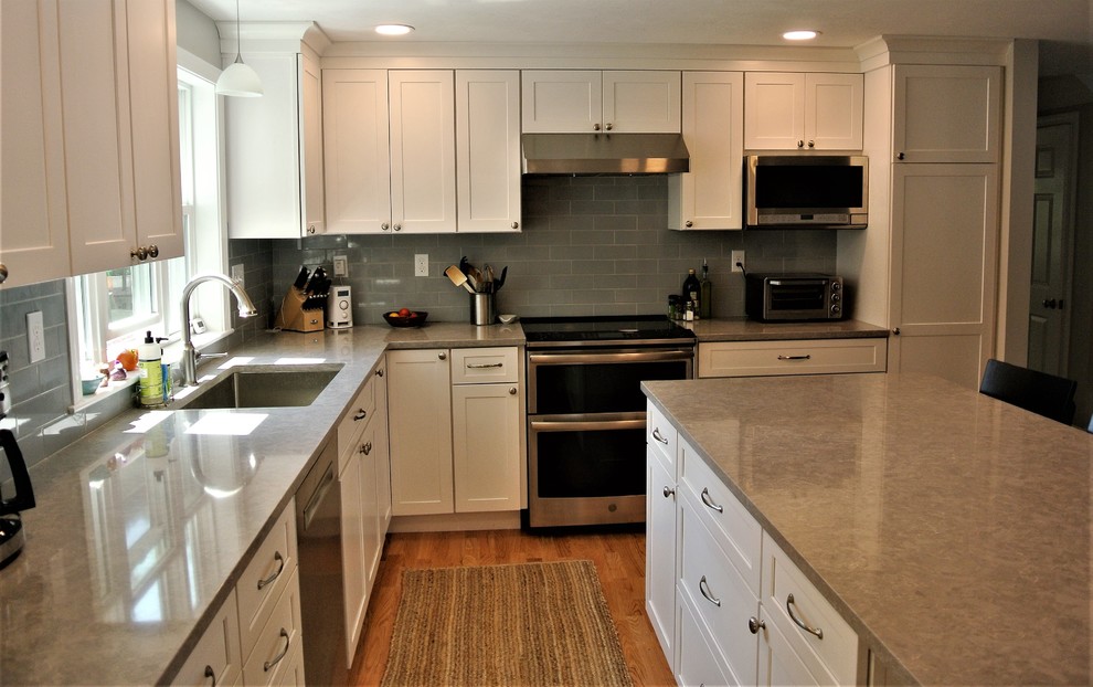 Inspiration for a transitional light wood floor kitchen remodel in Boston with an undermount sink, shaker cabinets, white cabinets, quartz countertops, gray backsplash, subway tile backsplash, stainless steel appliances, an island and gray countertops
