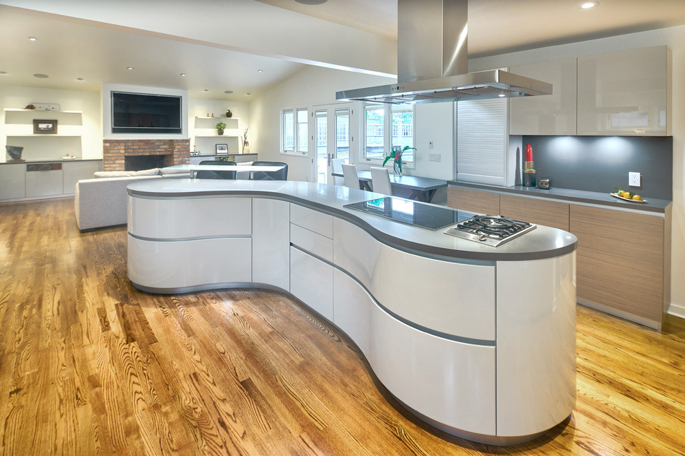 Contemporary open plan kitchen in San Francisco with flat-panel cabinets, medium wood cabinets, quartz benchtops, grey splashback, black appliances, light hardwood floors and with island.