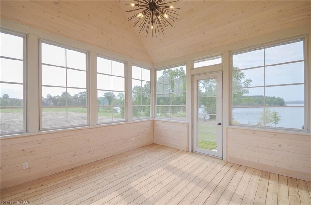 This is an example of a large country sunroom in Toronto with light hardwood floors, no fireplace, a standard ceiling and brown floor.