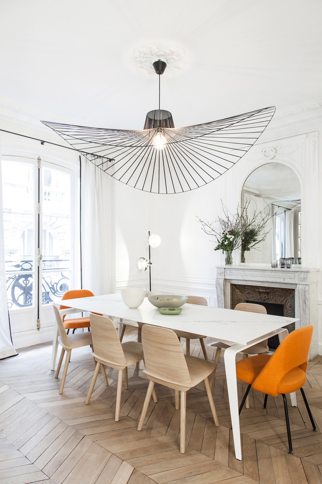 Photo of a scandinavian dining room in Paris with white walls, light hardwood floors and a standard fireplace.
